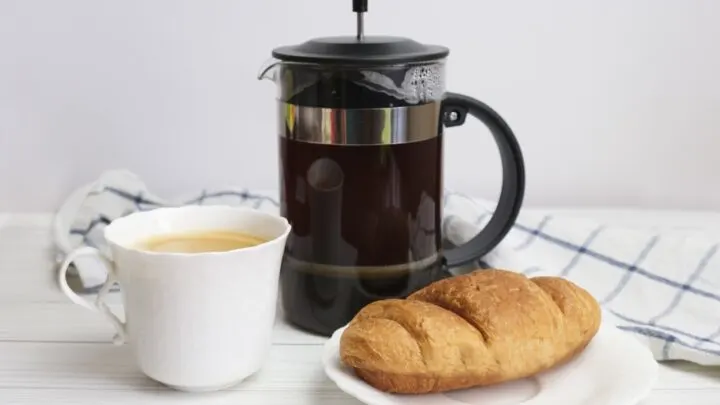A cup of delicious french press coffee, with a croissant. 