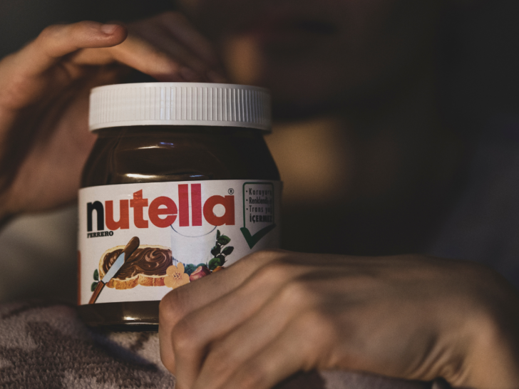 Person holding jar of Nutella for nutella coffee.